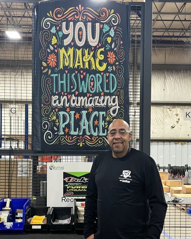 For Archie Moore, one of our Navitas Systems employees, no act is too small to bring a positive impact. That’s why two years ago, he chose to hang a sign in his warehouse that reads, “You Make This World An Amazing Place.”

“I was inspired to hang the sign to let my team know I care about their wellbeing, and we appreciate their daily hard work,” said Archie, who’s the Supply Chain Material Manager for our Navitas facilities in Ann Arbor, MI.

But the sign carries much more meaning. Archie and his wife, Kelli, bought two of the signs when shopping for the classes she teaches at Cesar Chavez Academy High School in Detroit, MI. Every April, known as Autism Acceptance Month, Kelli educates students about autism and organizes activities to help autistic and non-autistic students learn and interact with each other. 

Glowing under the warehouse ceiling lights, the colorful sign is often the first thing people see when visiting the warehouse.

“My team gets comments on the sign all the time,” said Archie, who has been with Navitas for four-and-a-half years.

East Penn would like to thank employees such as Archie for helping to build a more family-oriented environment—both in and outside of the workplace.